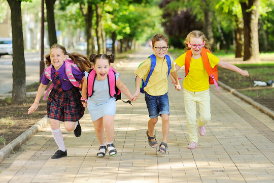 small schoolchildren with colorful school bags and backpacks run to school. Back to school, education, elementary school.