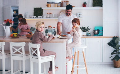 happy family with three kids having breakfast at home in the morning, cute kitchen interior