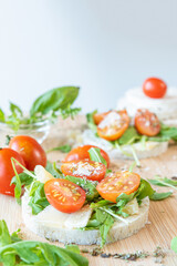 Angri, Italy. Food image of rice crackers snack with tomatoes, rocket salad, parmisan flakes,  oregano and olive oil, on a wooden cutting board. Italian food ingredients.