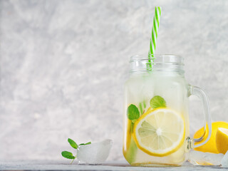 Icy refreshing summer homemade lemonade with lemon and mint on a gray table copy space