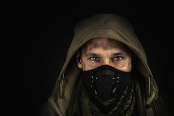 Dark photo of Young handsome man wearing black protactive face mask and hood