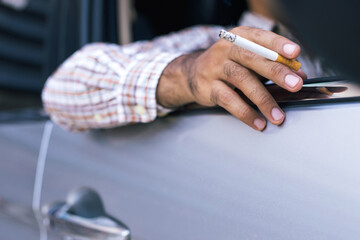 close up man hand hold smoking a cigarette in car while driving travel. 