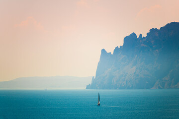 Beautiful blue sea and mountains in morning mist. Yacht sailing in the sea. Karadag volcano near...