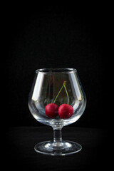 red cherries and a wine glass on a dark background