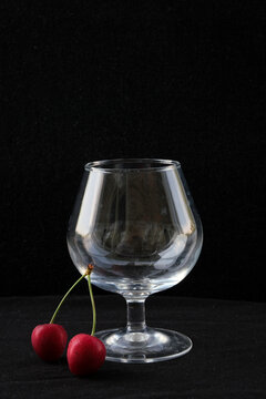 red cherries and a wine glass on a dark background