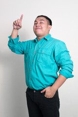 Young handsome overweight Asian businessman pointing up