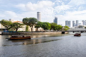 Singapore River with Cavenagh Bridge, only suspension bridge, tourist boats, trees on the river bank and Asian Civilisations Museum building.