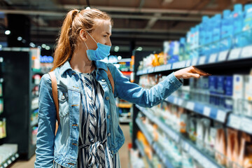 young woman in a medical protective mask on her face in a supermarket, a girl in the Department of...