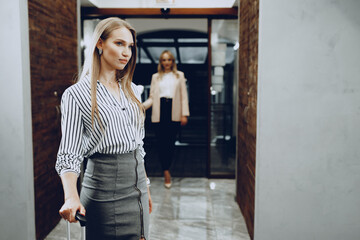 Two young women in formal clothes entering hotel lobby