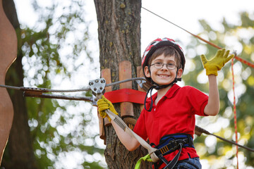 child climbs in a rope park. Boy In Adventure Park having fun in high wire park. Toddler Boy On A Ropes Course. Male toddler on zip line. Boy having a fun on Climbing Frame. Boyscout on a tree. Summer