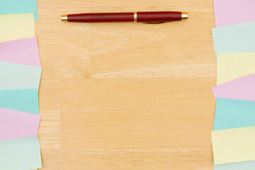 Sticky note background with multi-color notes and a pen on a wood desk