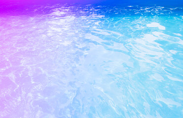 Fototapeta na wymiar Surface of blue swimming pool toned in multicolored neon. Background of blue ripped water in swimming pool. Neon background