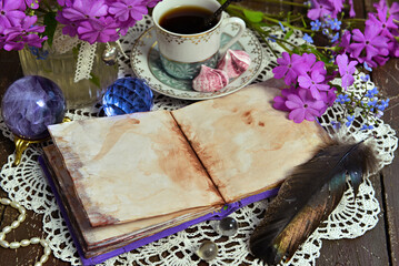 Cozy still life with open diary with blank pages, crystal, primrose flowers and cup of tea on...