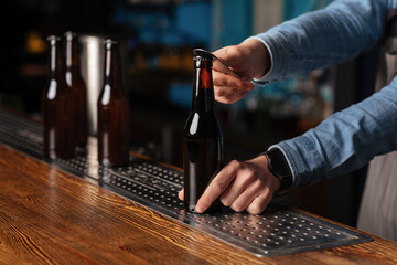 Beer order. Bartender hands open bottles on wooden bar counter