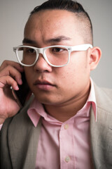 Obraz premium Face of young overweight Asian businessman with eyeglasses talking on the phone