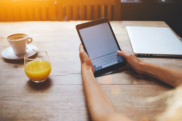 Closeup image of a woman's hands holding touch pad with blank copy space screen for your text message or advertising content, female using portable digital tablet while rest in comfortable coffee shop