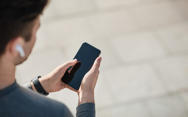 Favorite music for workout. Guy in modern wireless headphones and with tracker uses smartphone