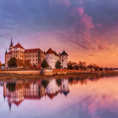Fototapeta na wymiar Wonderful sunrise view of Schloss Hartenfels, with colorful sky reflected in Elbe river . Picturesque morning view of castle on banks of the Elbe. Torgau. Saxony, Germany. creative Scenic image.