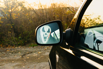 Halloween. A man in a terrible mask in a car in the driver's seat harvests pumpkins and scares.