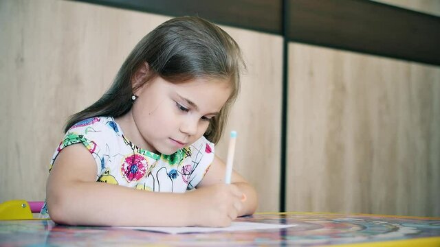 Happy little girl or cute primary child school child painting or writening on paper. Children elementary education concept.