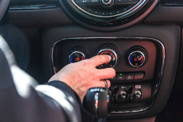 Obraz na płótnie Canvas Una mano manipula los botones de un salpicadero para gestionar el aire acondicionado del coche