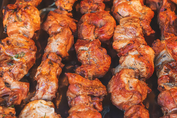 Fresh juicy grilled pieces of pork meat on skewers cooked on a charcoal grill. Barbecue in the street market outdoors. Closeup of fried meat with shallow depth of field.