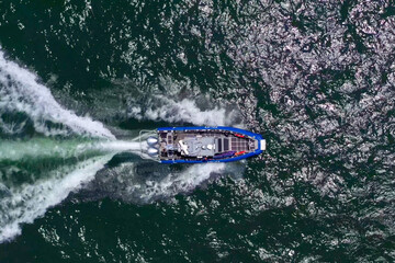Coastguard vessel patrolling the Sea at high speed, Top down aerial view.