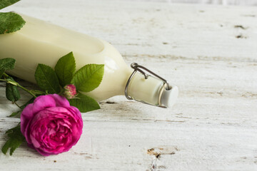 Ayurvedic drink pink milk or matcha. A glass bottle of milk lies on a table with a pink rose. Top view