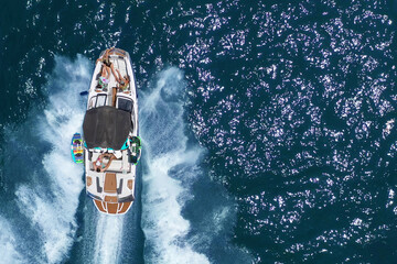 Speed boat with people roaring across the Sea at high speed, Aerial view.