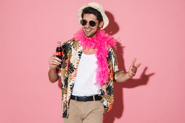 Portrait of cheerful young man wearing boa dancing while drinking soda
