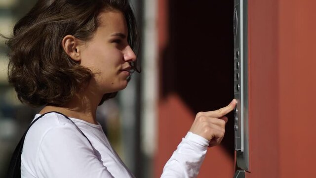 Girl presses the intercom button in the house
