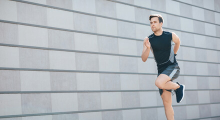 Fototapeta na wymiar Cardio training in city. Young man in sportswear runs fast