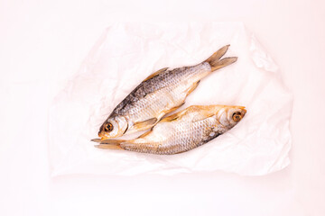 Two dried fishes in white paper on the white background