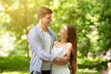 Attractive loving couple hugging and looking at each other in summer park