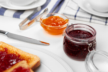 Photo of kitchen table with toasts, fruit jams and knife