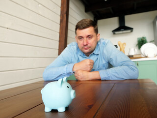 A man looks at the piggy bank. Problems with savings, bankruptcy or insolvency concept.