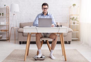 Video call and working from home. Man in glasses, shirt, shorts and socks at workplace, with dumbbell