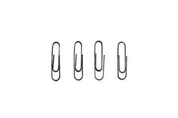 Four silver paper clips isolated on white studio background. Paper clip background / texture
