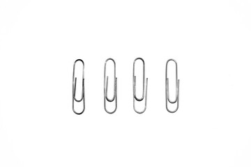 Four silver paper clips isolated on white studio background. Paper clip background / texture
