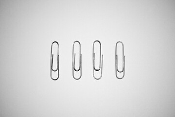 Four silver paper clips isolated on white studio background. Paper clip background / texture
