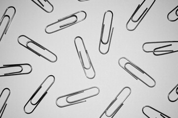 Many silver paper clips isolated on white studio background. Paper clip background / texture
