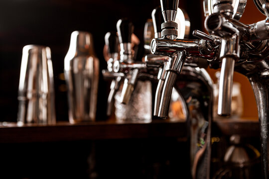 Metal taps for craft beer and bartender tools in interior of pub