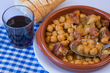 Plato de garbanzos compuestos junto a un vaso de vino