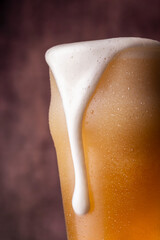 Pint of cold pale beer with leaking froth