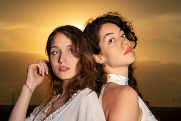 Beautiful young girls posing together at sunset in a sunflower field