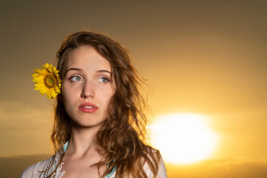 Beautiful young girl posing in a sunflower field at sunset