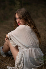 Beautiful young girl wearing a lace top posing in a dark forest