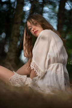 Beautiful young girl wearing a lace top posing in a dark forest