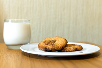 A plate of cookies and a glass of milks placed on a table.