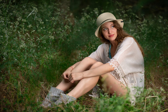 Beautiful young girl with a straw hat posing in a dark forest